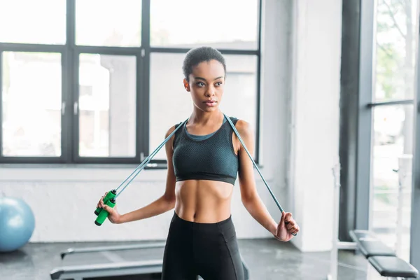Portrait of young african american sportswoman with jumping rope at gym — Stock Photo