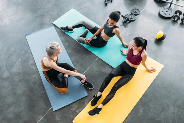 Overhead view of young multicultural sportswomen resting on mats after training at gym — Stock Photo