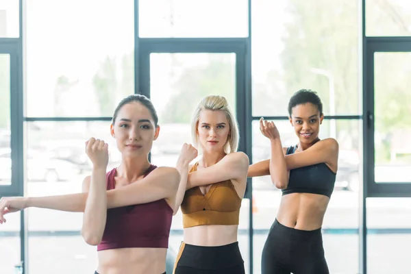 Porträt attraktiver multiethnischer Sportlerinnen, die sich dehnen, bevor sie im Fitnessstudio trainieren — Stockfoto