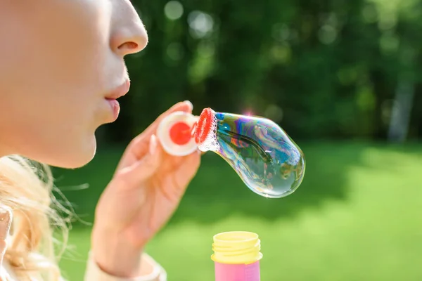 Colpo ritagliato di giovane donna che soffia bolle di sapone nel parco — Foto stock