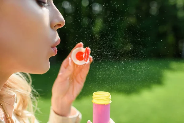 Seitenansicht einer jungen Frau, die im Park Seifenblasen pustet — Stockfoto