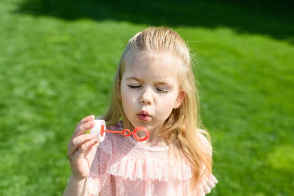 Adorable little child blowing soap bubbles in park — Stock Photo