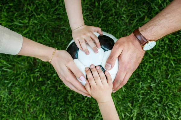 Cropped shot of family with two kids touching soccer ball on grass — Stock Photo