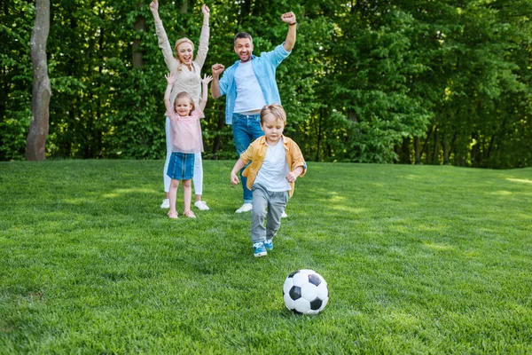 Família feliz jogando com bola de futebol no parque — Fotografia de Stock