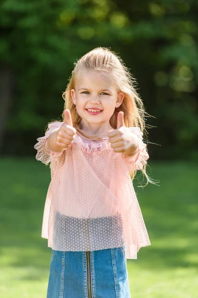 Mignon petit enfant montrant pouces levés et souriant à la caméra — Photo de stock