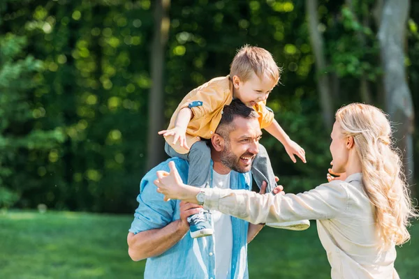 Glückliche Eltern mit entzückendem kleinen Sohn verbringen Zeit miteinander im Park — Stockfoto
