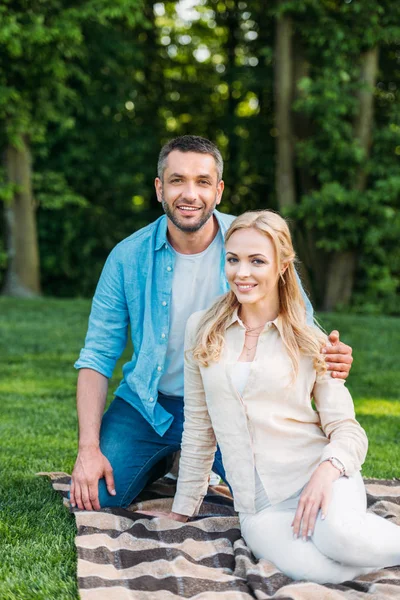 Feliz pareja sonriendo a la cámara en el picnic en el parque - foto de stock