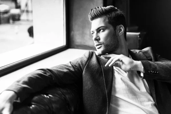 Young stylish man looking away while sitting on couch at barber shop — Stock Photo