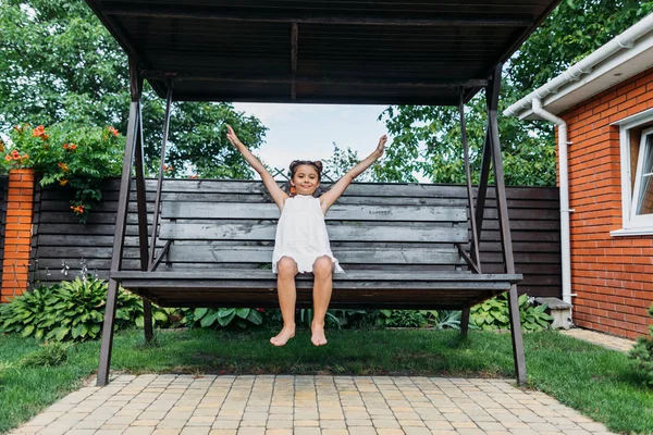 Mignon petit enfant avec les bras tendus reposant sur un banc en bois dans la journée d'été — Photo de stock