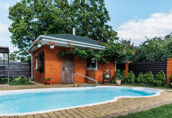 Casa di campagna in legno con piscina vicino, alberi e cielo nuvoloso — Foto stock