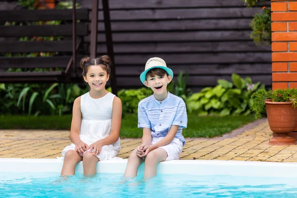 Allegri fratellini che riposano vicino alla piscina il giorno d'estate — Foto stock