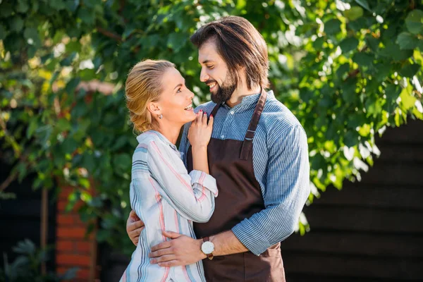 Feliz pareja abrazándose y mirándose en el patio trasero en el día de verano - foto de stock