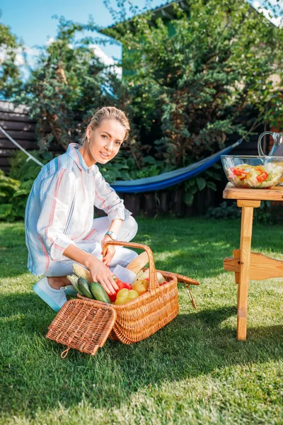 Mulher com cesta cheia de legumes frescos para piquenique no quintal — Fotografia de Stock