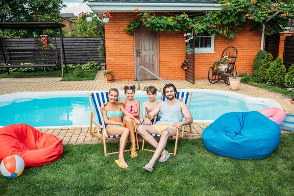 Smiling family spending time near swimming pool at countryside backyard on summer day — Stock Photo