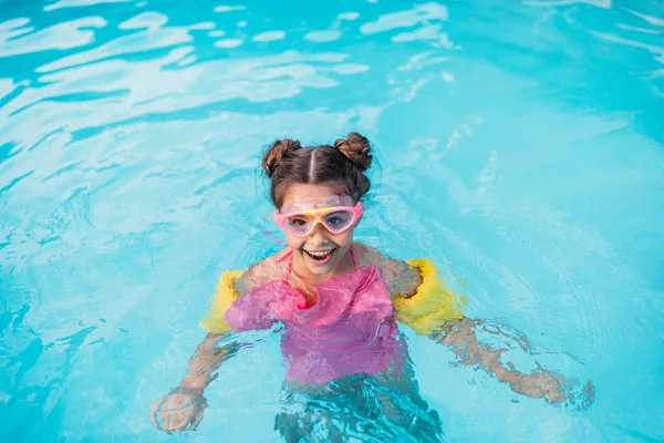 Portrait of smiling kid in mask with water wing swimming in swimming pool on summer day — Stock Photo