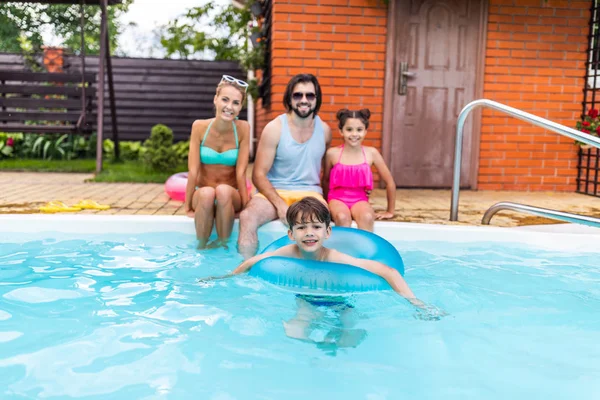 Selective focus of happy family spending time near swimming pool at countryside backyard on summer day — Stock Photo