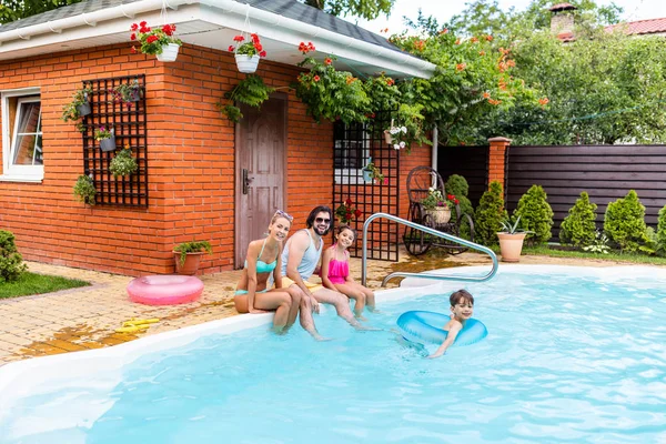 Happy family spending time near swimming pool at countryside backyard on summer day — Stock Photo