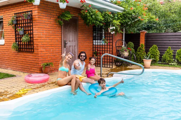 Famille montrant pouces levés tout en passant du temps près de la piscine le jour de l'été — Photo de stock