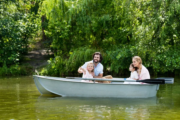 Jeune famille passer du temps ensemble en bateau sur la rivière au parc et regarder loin — Photo de stock