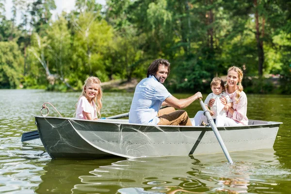 Beautiful young family spending time together in boat on river at park — Stock Photo