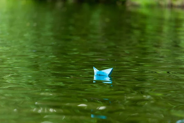 Nahaufnahme eines auf der Wasseroberfläche schwimmenden blauen Papier-Origami-Bootes — Stockfoto