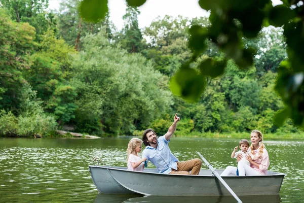 Счастливая молодая семья проводит время вместе в лодке на озере в парке — стоковое фото