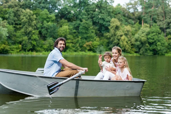 Vue latérale de la jeune famille équitation bateau sur le lac au parc — Photo de stock