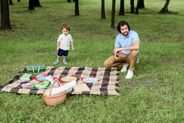 Hermoso feliz padre con pequeño hijo teniendo picnic en el parque - foto de stock