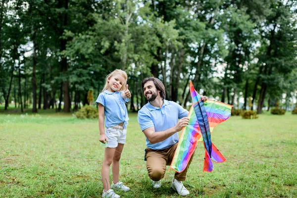 Bell'uomo felice padre con aquilone e adorabile figlioletta trascorrere del tempo insieme al parco — Foto stock