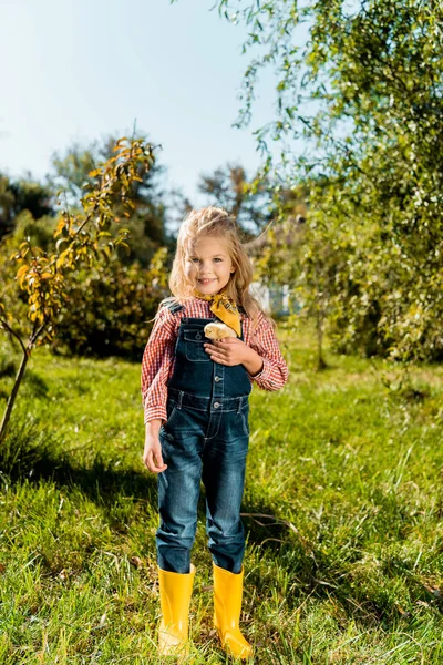 Happy cute child holding adorable yellow baby chick outdoors — Stock Photo
