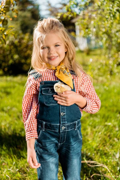 Selective focus of child holding adorable yellow baby chick outdoors — Stock Photo