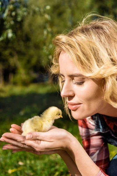 Sorrindo mulher segurando adorável amarelo bebê pinto ao ar livre — Fotografia de Stock