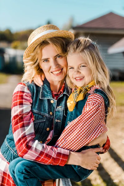 Портрет привлекательной фермерши, обнимающей маленькую дочь на ферме — стоковое фото