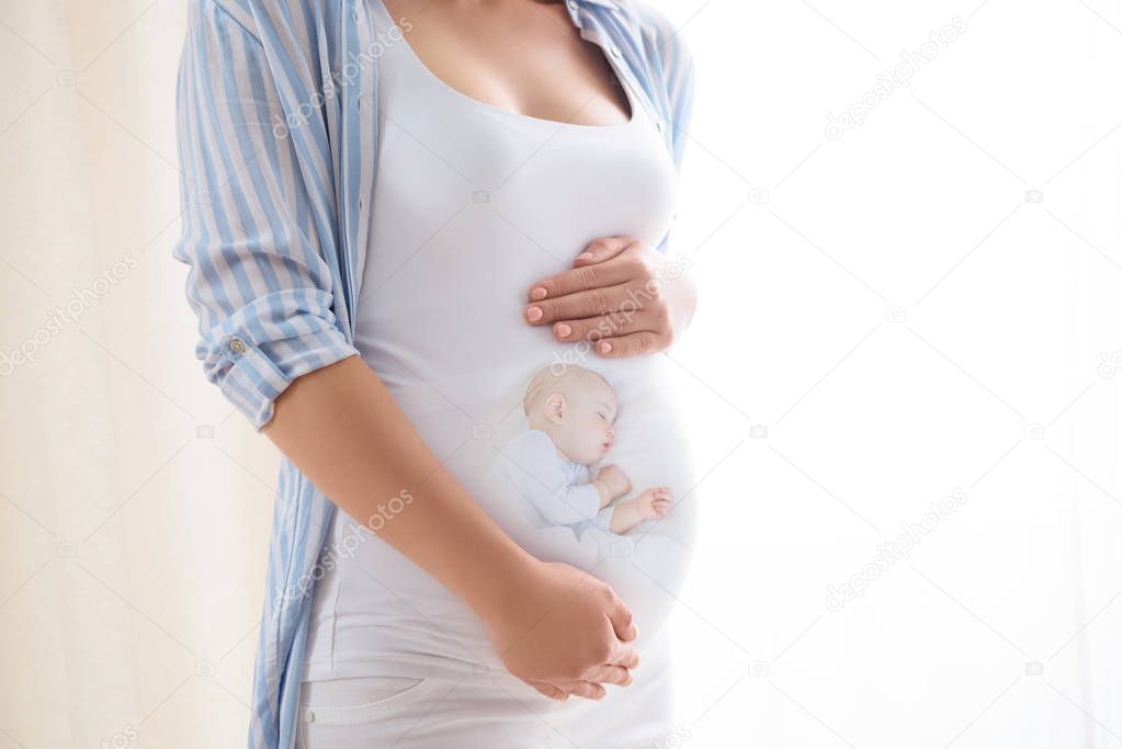 partial view of pregnant woman carefully palming belly with baby 