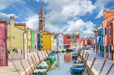 Venedik, İtalya 'daki ünlü Burano adasında renkli evler, kanal, tekne ve kilise manzarası