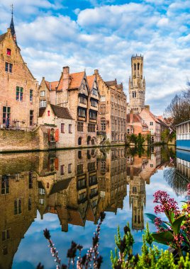 Belçika, Bruges 'deki bir kanal boyunca ünlü çan kulesi ve ortaçağ binalarıyla manzara