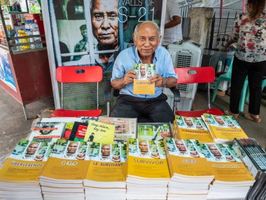 Phnom Penh, Cambodia - November 13, 2019: Chum Mey presents the book about the period in which he was a prisoner in Tuol Sleng, Phnom Penh, Cambodia clipart