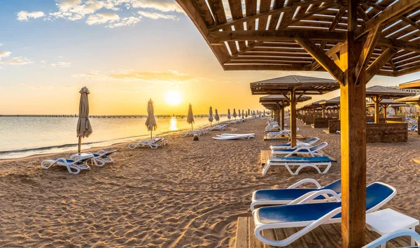 Mısır, Hurghada 'da gün doğumunda Kızıl Deniz plajında güneşli yataklar ve şemsiyeli manzara