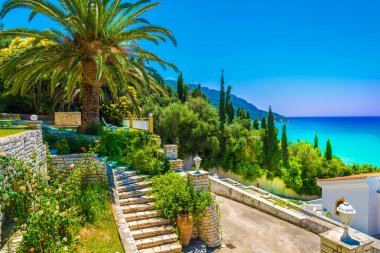 Yunanistan 'ın Korfu adasındaki Agios Georgios Pagon köyündeki palmiye ağacı ve ev manzarası