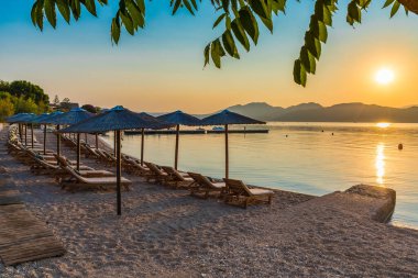 Gün batımında sandalyeli ve şemsiyeli Nikiana plajı, Lefkada Adası, Yunanistan