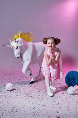 çocuk moda kavramı. romantik kız pembe. küçük bir lolipop yiyor. tek boynuzlu at origami.