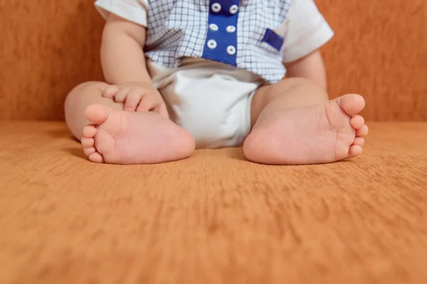 Childs nohy na postel oranžové pozadí. Malé roztomilé bosé nohy. Dětská podpatky. Přední čistý prostor pro text, kopie prostor. — Stock fotografie