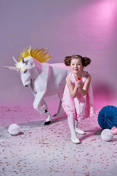çocuk moda kavramı. romantik kız pembe. küçük bir lolipop yiyor. tek boynuzlu at origami.