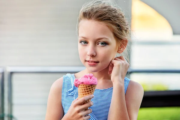 Portrét, okouzlující dívek 9-10 let letní den. Mladá atraktivní dáma drží zmrzlinu růžová ručně se dívá na kameru. Lahodný studený dezert v horn vafle. — Stock fotografie