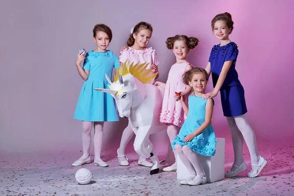 Grupa mała dziewczynka w piękny różowy, niebieski sukienki następnego z postacią jednorożca. Pięcioro dzieci Pani razem, ubrania, katalog kolekcji mody. Wesoły dziewczyny, studio, pastelowe tło. Modele 5 dzieci. — Zdjęcie stockowe