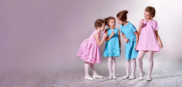 Grupo niña en hermosos vestidos de color rosa azul.Cuatro niños anuncian ropa para el catálogo de prendas de vestir. Estudio, pancarta de fondo pastel, espacio de copia para texto, tienda, publicidad. Concepto modelos de moda niños . — Foto de Stock
