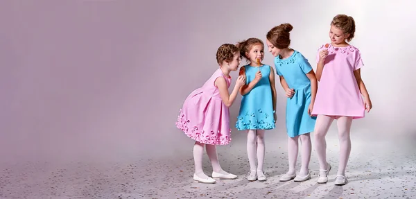Güzel pembe, mavi elbiseler grup küçük kız. Dört çocuk giyim giyim kataloğu için reklam. Stüdyo, pastel arka plan afiş, metin, Dükkanı, reklam için yer kopyalayın. Kavram moda modelleri çocuklar.