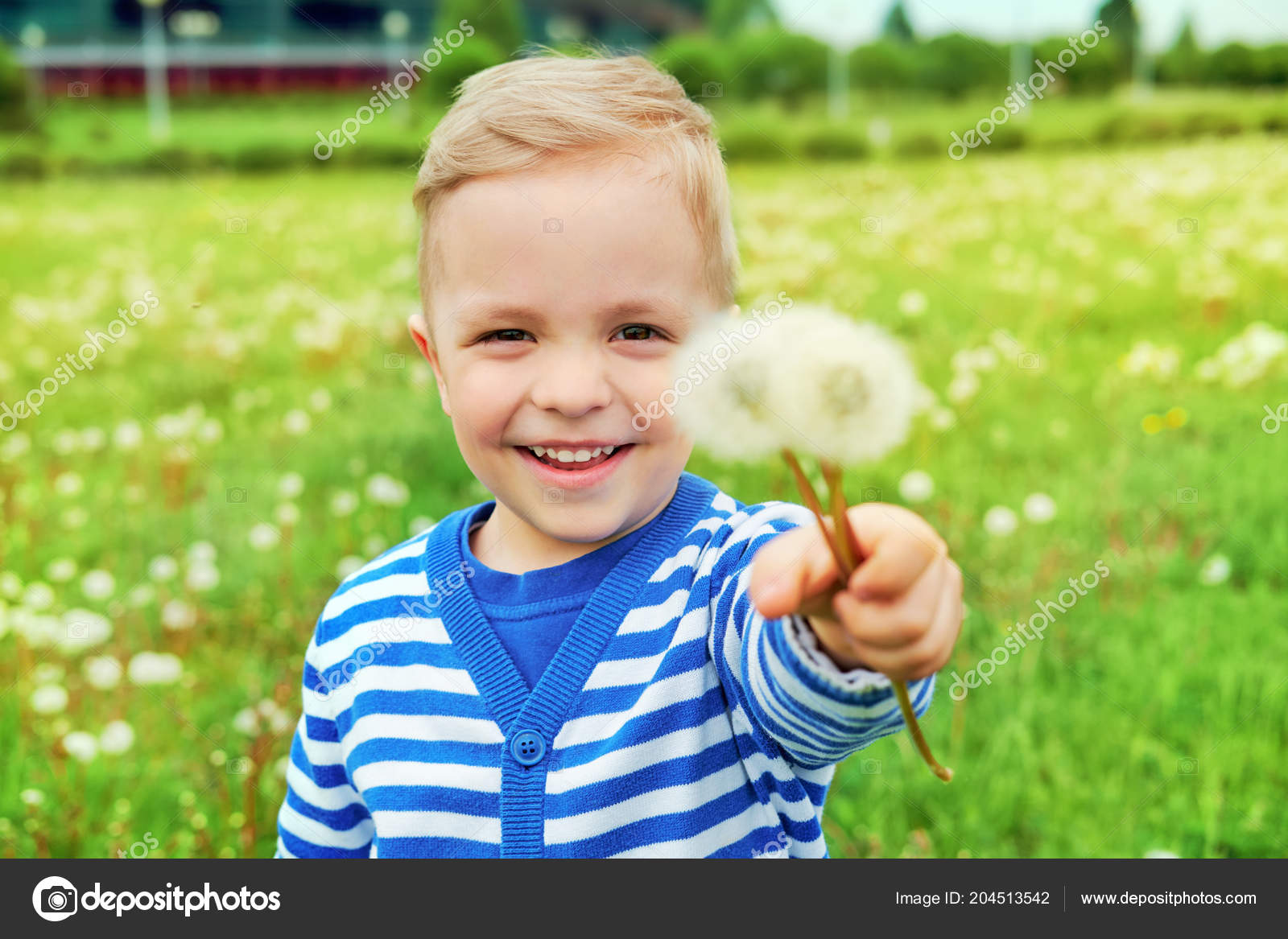 Happy kid standing in grass with dandelions. Portrait happy child outdoors in nature summer day, vacation. Emotion face little boy. Background green grass. Joyful childhood. Lifestyle. Stock Photo by ©Valendina