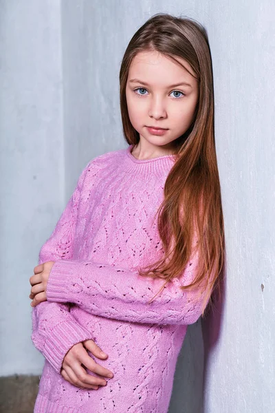 Şık model pembe kazaklı çocuk. Portre sevimli moda kız çocuk. Beton beyaz duvara yakın poz genç görünüyor ciddi, kendinden emin. moda kavramı.