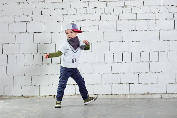 Cool çocuk çocuk hip hop aktif müzik dans. Şık sevimli. Rapçi ufaklık şapkası, spor ayakkabı, pantolon, tişört, sokak stili kıyafetler giyer. Stüdyo, tuğla duvar arka plan.